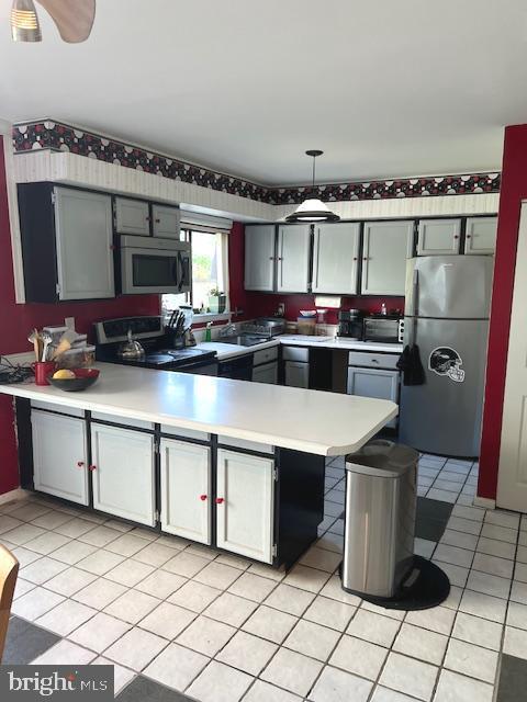 kitchen with ceiling fan, stainless steel appliances, light tile patterned floors, and gray cabinetry