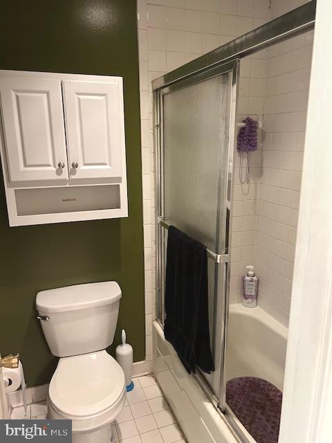 bathroom featuring toilet, shower / bath combination with glass door, and tile patterned floors