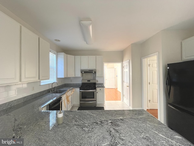 kitchen featuring black fridge, wood-type flooring, stainless steel range oven, white cabinets, and sink