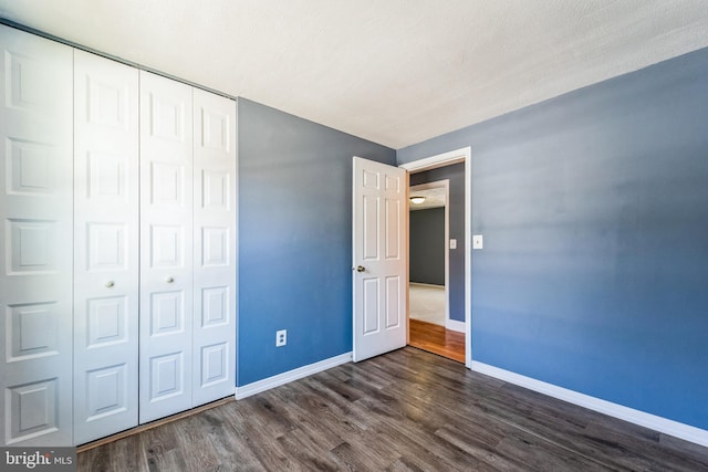 unfurnished bedroom featuring dark hardwood / wood-style floors and a closet