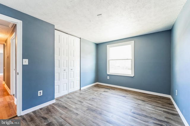 unfurnished bedroom featuring wood-type flooring, a closet, and a textured ceiling