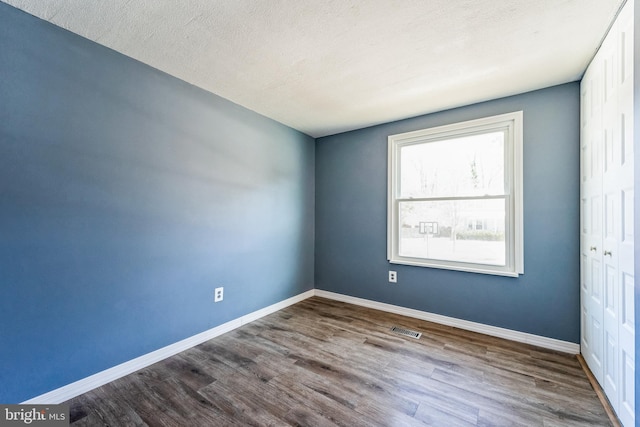 spare room featuring wood-type flooring and a textured ceiling