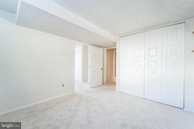 unfurnished bedroom with a closet, light carpet, and a textured ceiling