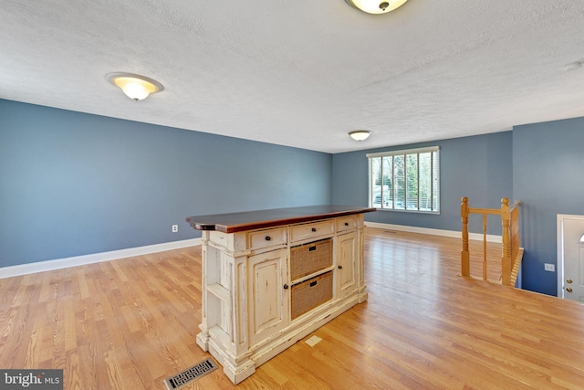 kitchen featuring light brown cabinetry, a center island, light hardwood / wood-style floors, and a textured ceiling