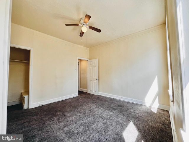 unfurnished bedroom with ceiling fan, dark carpet, a closet, and crown molding