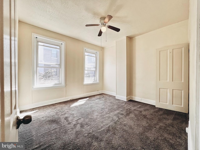 unfurnished room with ceiling fan, plenty of natural light, a textured ceiling, and dark colored carpet