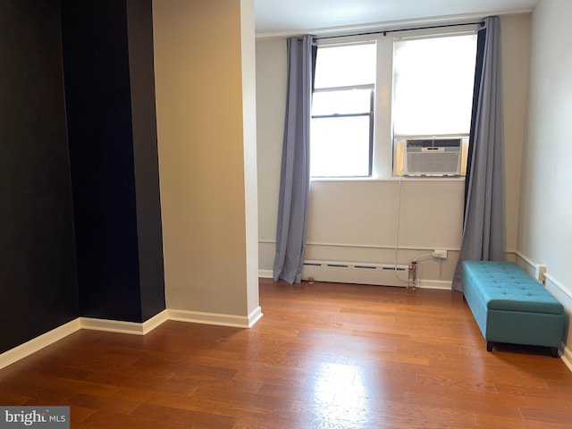 empty room featuring hardwood / wood-style floors, plenty of natural light, cooling unit, and baseboard heating