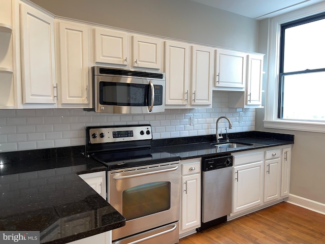 kitchen featuring sink, white cabinetry, stainless steel appliances, tasteful backsplash, and light wood-type flooring