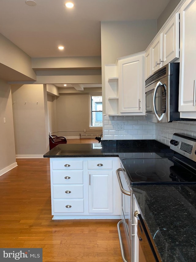 kitchen featuring white cabinets, dark stone counters, decorative backsplash, light hardwood / wood-style floors, and stainless steel appliances