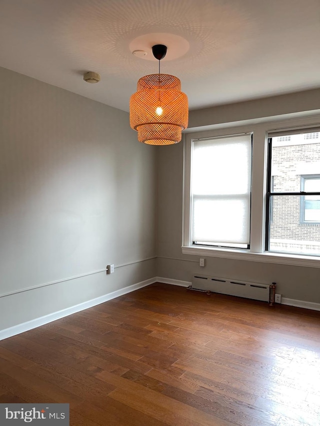 spare room featuring dark hardwood / wood-style flooring and a baseboard heating unit