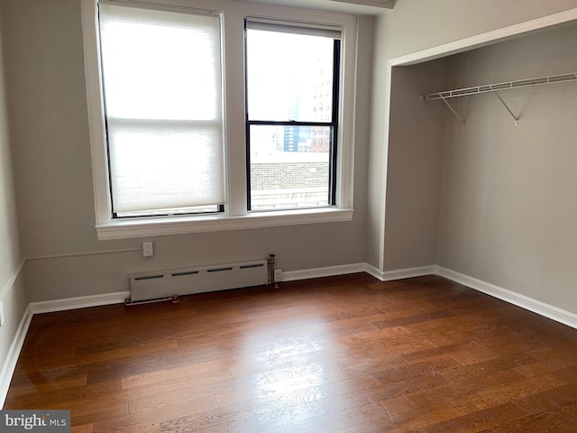 interior space featuring baseboard heating, dark wood-type flooring, and a closet