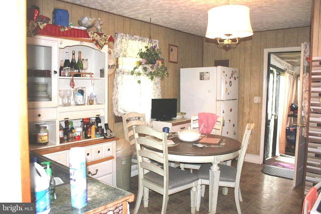 dining area with a textured ceiling and wood walls