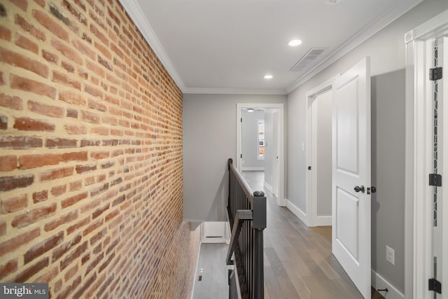 hall featuring brick wall, ornamental molding, and hardwood / wood-style floors