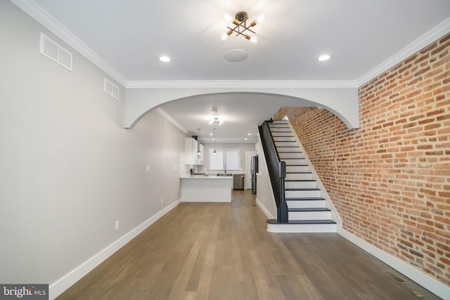 interior space with dark wood-type flooring, brick wall, and crown molding