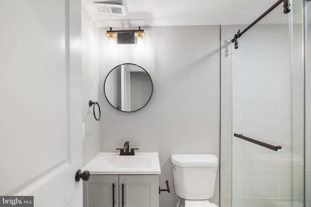 bathroom with toilet, vanity, and tiled shower