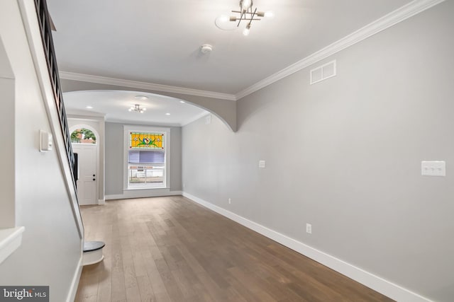 hall with hardwood / wood-style floors, crown molding, and a notable chandelier