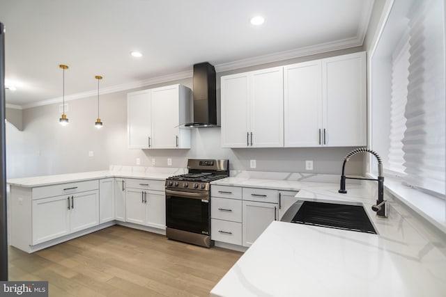 kitchen with pendant lighting, white cabinets, wall chimney exhaust hood, and stainless steel gas range oven