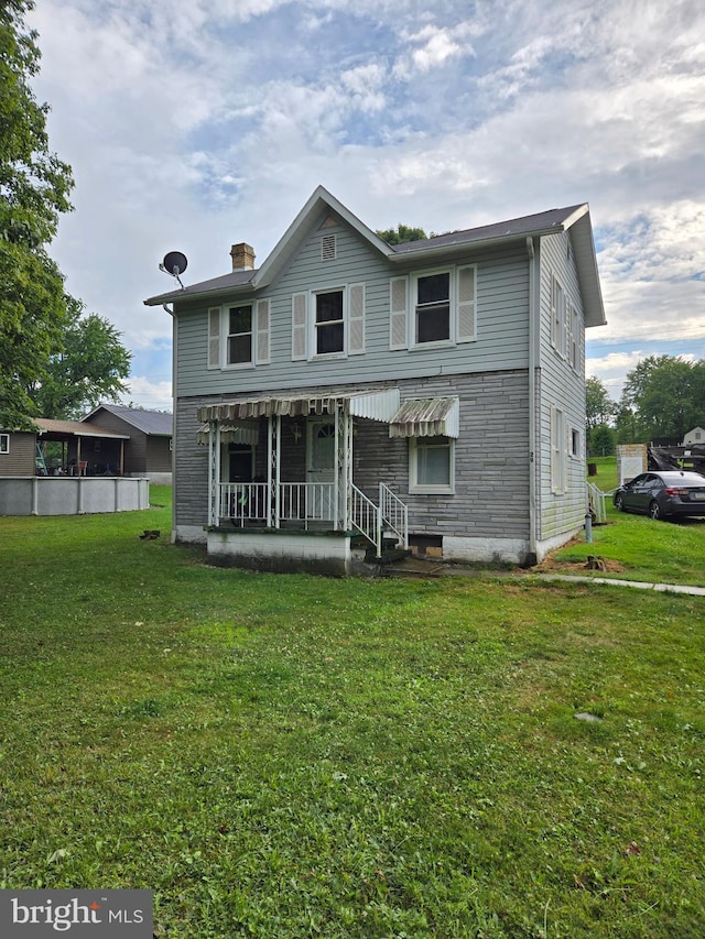 back of house featuring a lawn and a porch