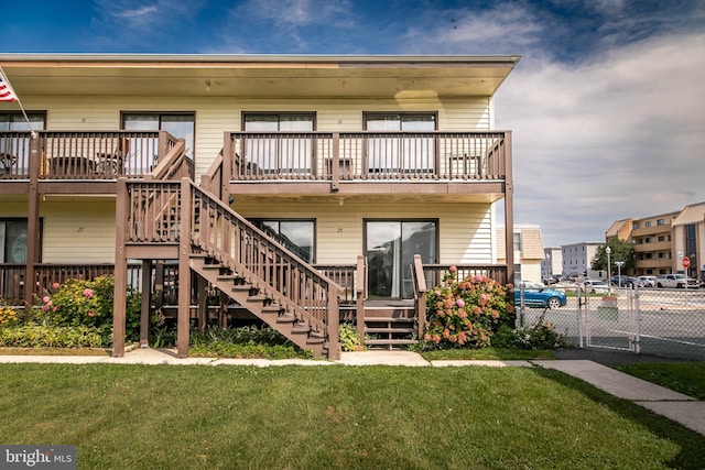 back of property featuring a balcony and a lawn