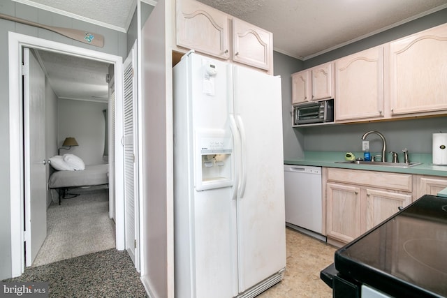 kitchen featuring a textured ceiling, light brown cabinetry, white appliances, and a sink