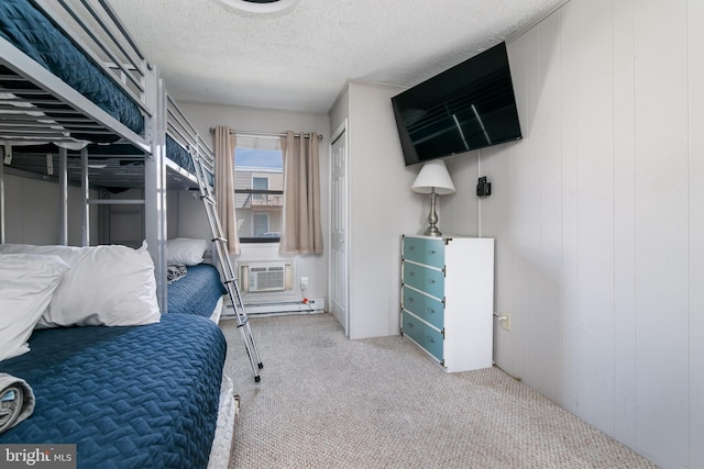 bedroom with a wall mounted air conditioner, light colored carpet, and a textured ceiling