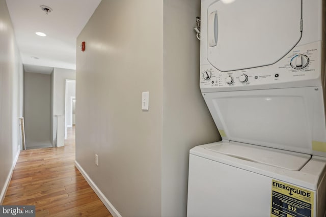 washroom with light hardwood / wood-style flooring and stacked washer / dryer