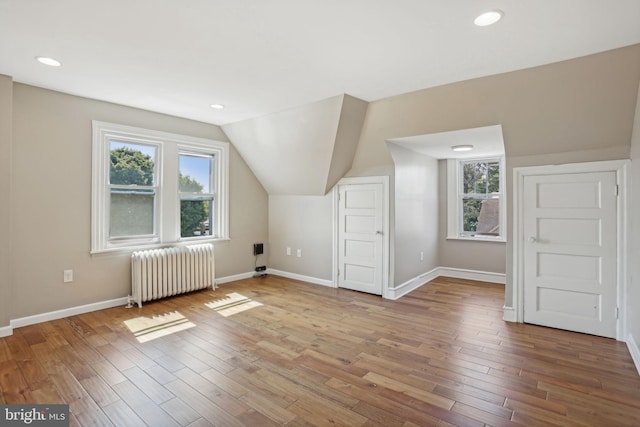 additional living space featuring vaulted ceiling, hardwood / wood-style floors, and radiator heating unit