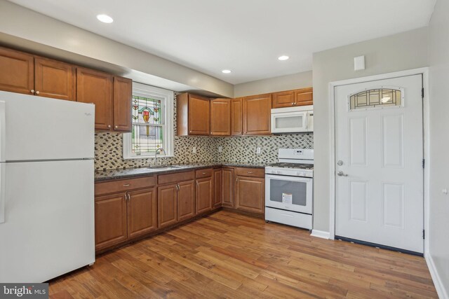 kitchen featuring white appliances, tasteful backsplash, wood-type flooring, and sink