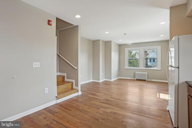 unfurnished living room featuring light wood-type flooring and radiator heating unit