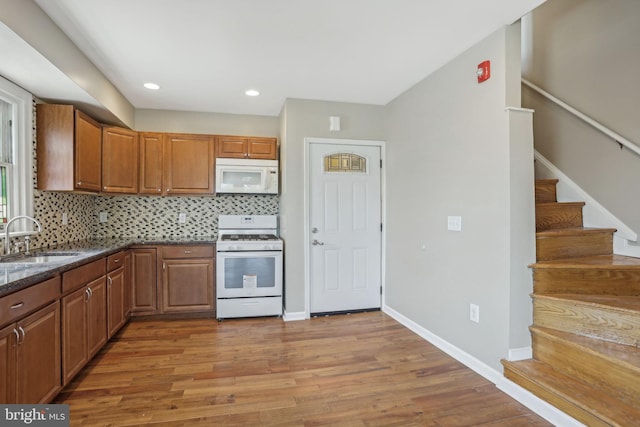 kitchen featuring hardwood / wood-style floors, white appliances, backsplash, and sink