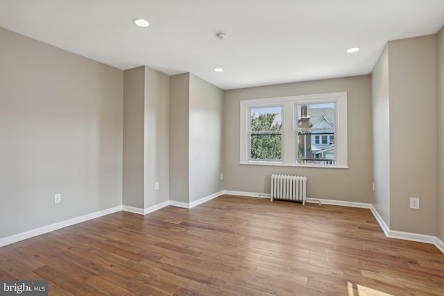 empty room with hardwood / wood-style flooring and radiator