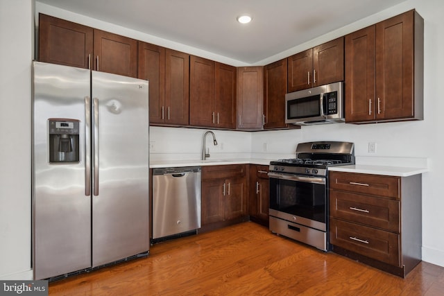 kitchen featuring sink, hardwood / wood-style floors, dark brown cabinetry, and stainless steel appliances