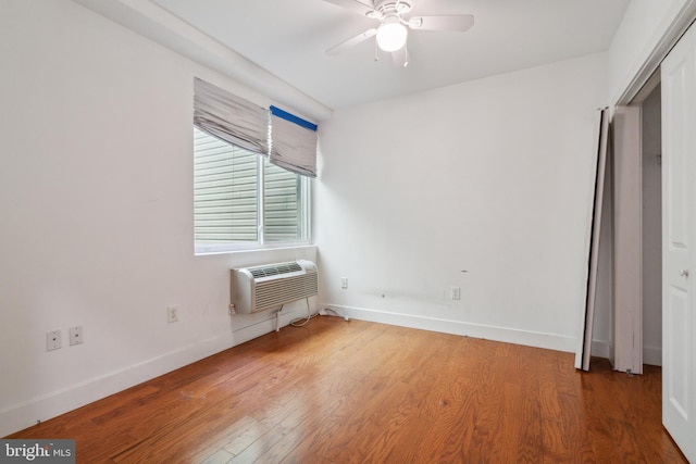 unfurnished bedroom with ceiling fan, a closet, wood-type flooring, and an AC wall unit