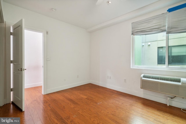 unfurnished room with a wall mounted AC and wood-type flooring