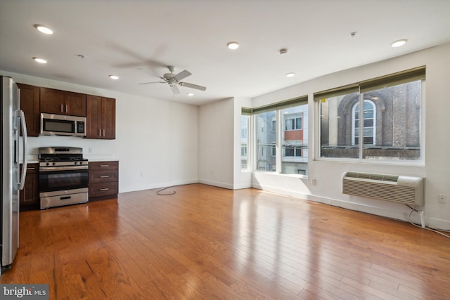 kitchen featuring ceiling fan, an AC wall unit, stainless steel appliances, and light hardwood / wood-style flooring