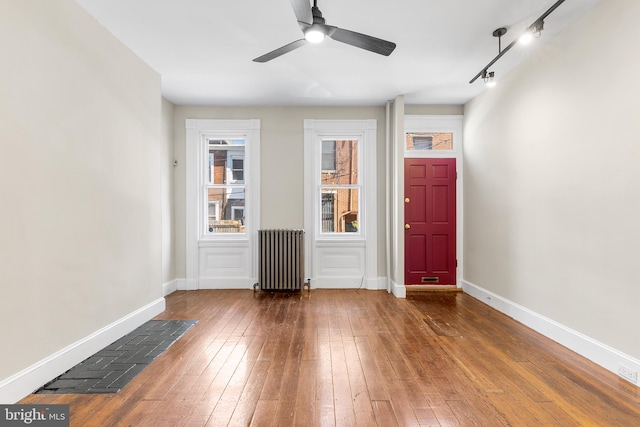 foyer entrance with hardwood / wood-style flooring, radiator, and rail lighting