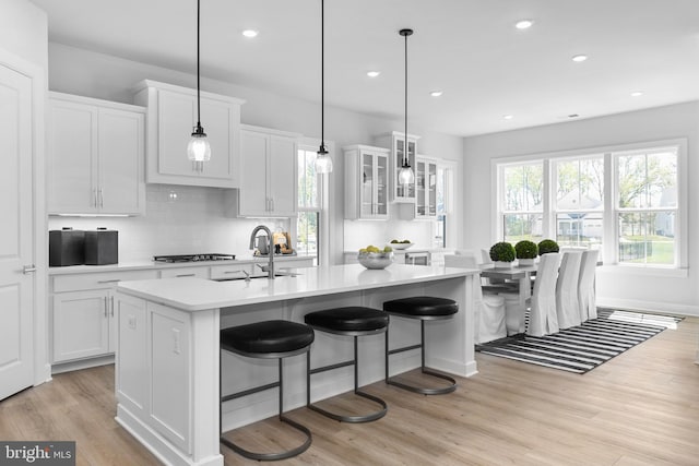 kitchen featuring white cabinets, an island with sink, light hardwood / wood-style flooring, and stainless steel gas cooktop