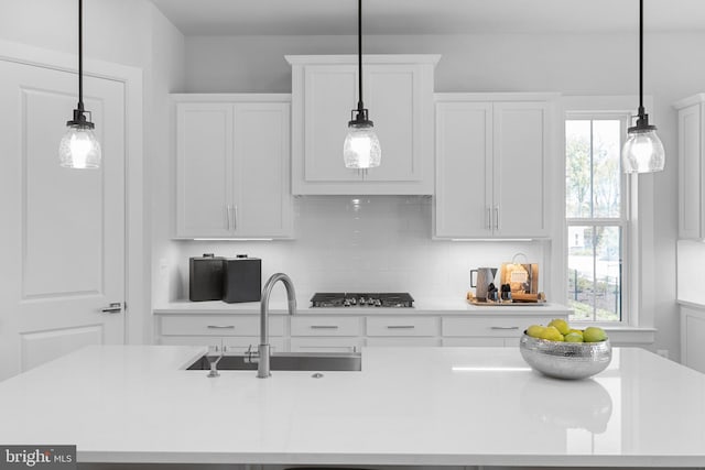 kitchen featuring white cabinets, sink, decorative light fixtures, stainless steel gas stovetop, and decorative backsplash