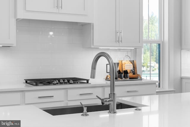 kitchen with white cabinets, tasteful backsplash, and sink