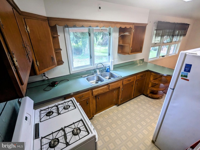 kitchen with light tile patterned floors, sink, stove, and white fridge