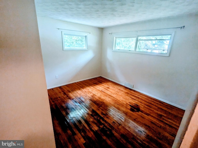 spare room with a textured ceiling and wood-type flooring