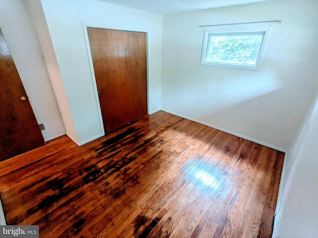 unfurnished bedroom with a closet and hardwood / wood-style flooring