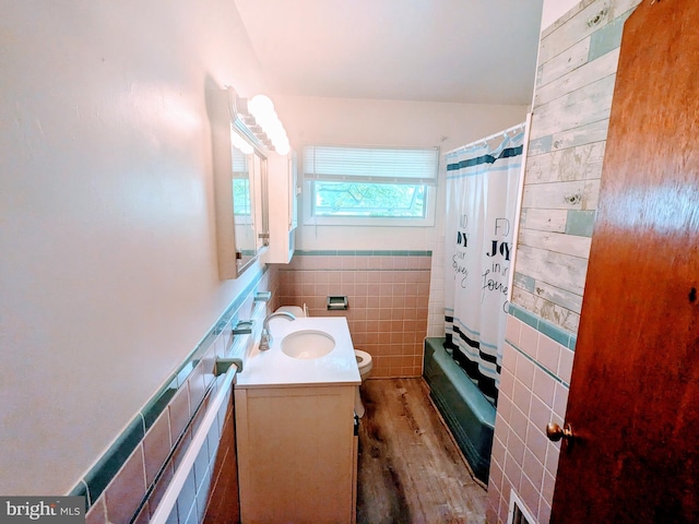 full bathroom featuring toilet, vanity, tile walls, hardwood / wood-style flooring, and shower / tub combo with curtain