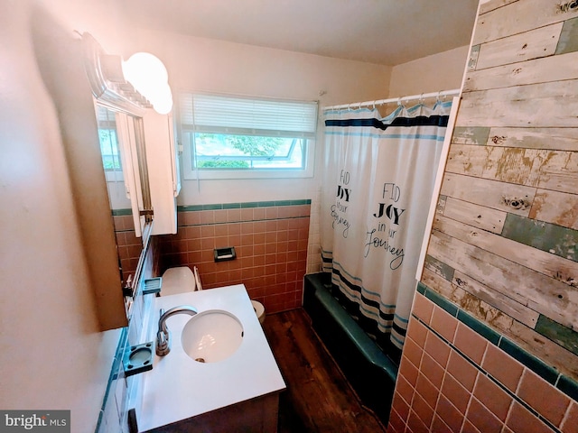 full bathroom featuring hardwood / wood-style floors, vanity, shower / bathtub combination with curtain, tile walls, and toilet