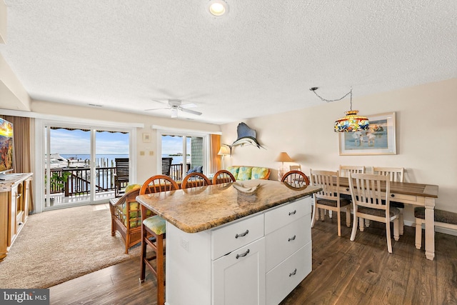 kitchen featuring decorative light fixtures, dark hardwood / wood-style flooring, white cabinets, and a kitchen island