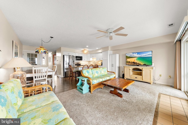 carpeted living room featuring a textured ceiling and ceiling fan