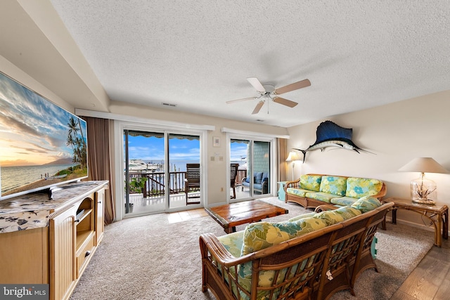 living room featuring a textured ceiling, ceiling fan, and hardwood / wood-style flooring