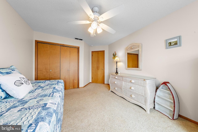 carpeted bedroom featuring a closet, a textured ceiling, and ceiling fan