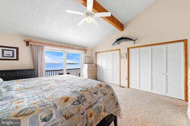 carpeted bedroom featuring ceiling fan, a water view, lofted ceiling with beams, a textured ceiling, and access to exterior