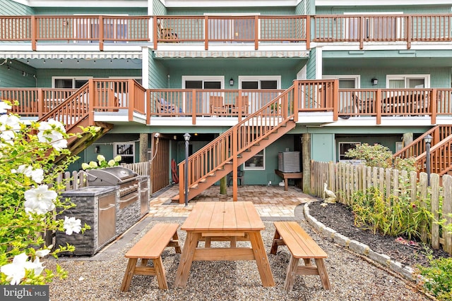 rear view of house with a wooden deck and a patio